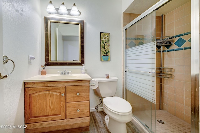 bathroom featuring toilet, a shower stall, baseboards, and vanity