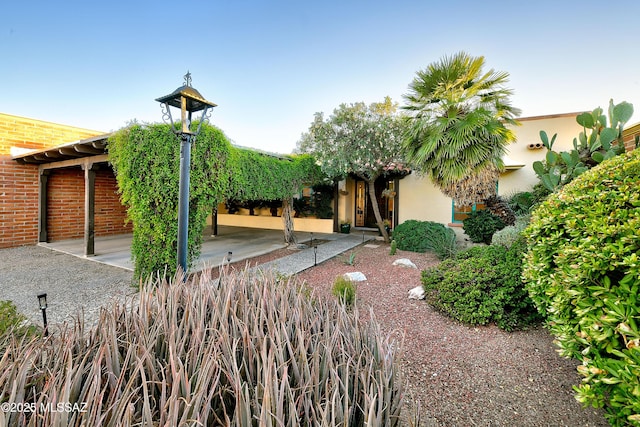 exterior space featuring brick siding, a patio, and stucco siding