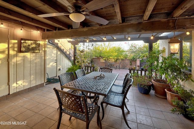 view of patio with a ceiling fan, outdoor dining space, and stairway