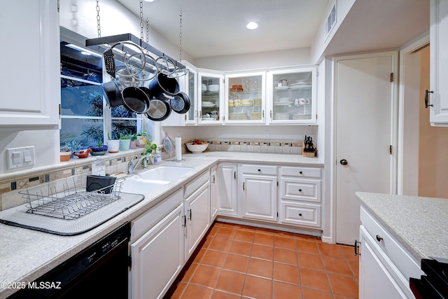 kitchen featuring black dishwasher, glass insert cabinets, light countertops, a sink, and light tile patterned flooring