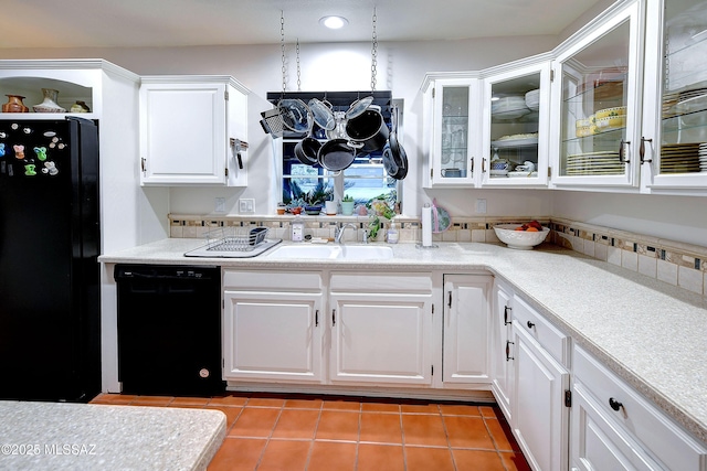 kitchen with light tile patterned flooring, a sink, white cabinets, light countertops, and black appliances