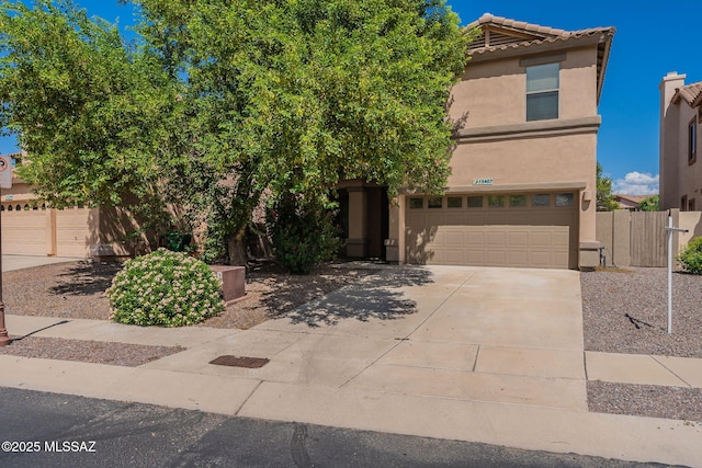 view of front of property featuring a tile roof, stucco siding, concrete driveway, fence, and a garage