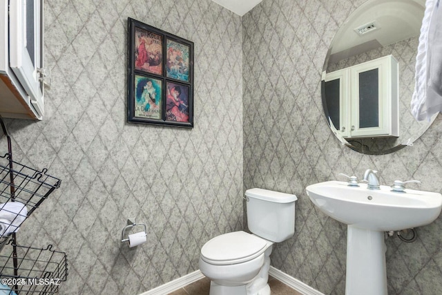 half bath featuring toilet, baseboards, and visible vents