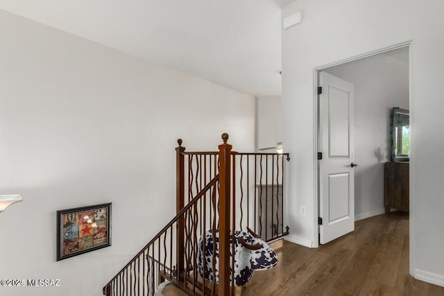 hallway featuring wood finished floors, an upstairs landing, and baseboards