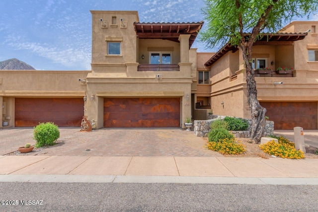 southwest-style home with a garage, decorative driveway, and stucco siding