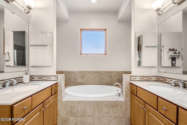 bathroom featuring a garden tub, two vanities, and a sink