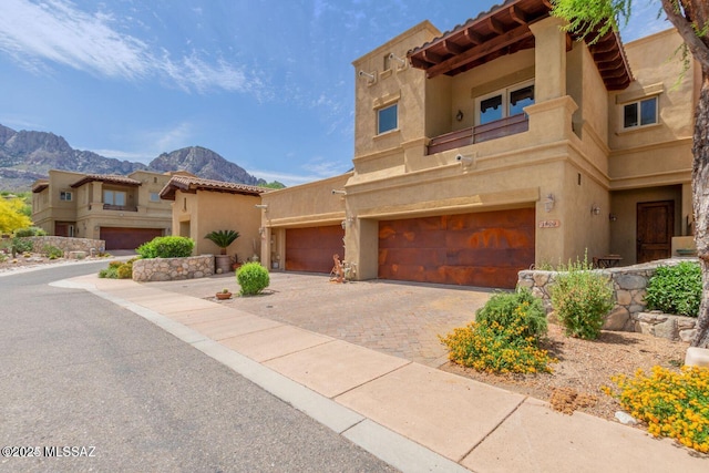 view of front of house with decorative driveway, a mountain view, a tiled roof, and stucco siding