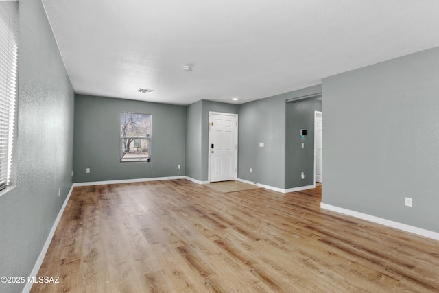 spare room with light wood-style floors, visible vents, and baseboards