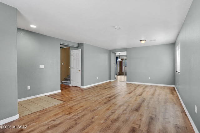 empty room featuring stairs, baseboards, and wood finished floors