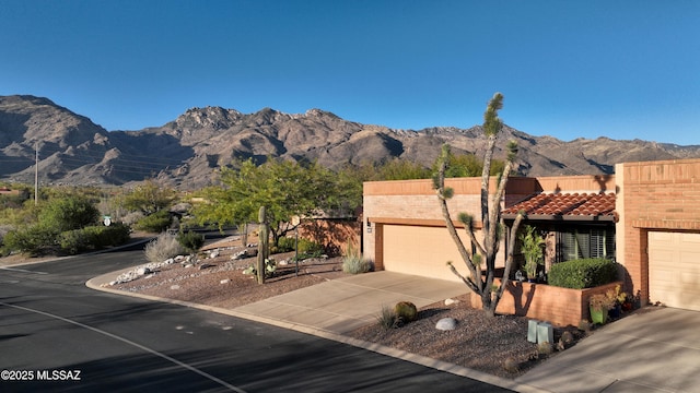 view of front of house with a mountain view, a tile roof, driveway, and a garage