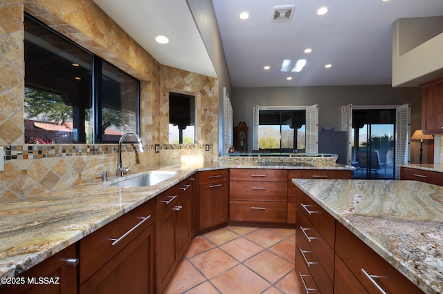 kitchen featuring visible vents, light stone counters, a sink, backsplash, and light tile patterned flooring