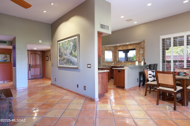 kitchen featuring light tile patterned flooring, recessed lighting, a peninsula, brown cabinets, and tasteful backsplash