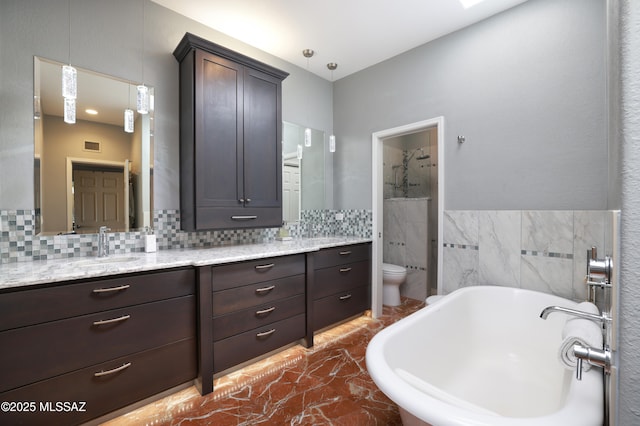 full bathroom with marble finish floor, a freestanding bath, toilet, vanity, and walk in shower