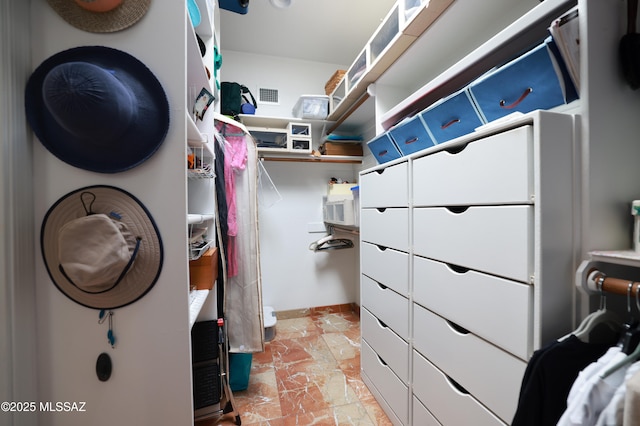 walk in closet featuring stone finish floor and visible vents