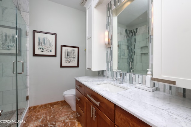 full bathroom featuring marble finish floor, toilet, a shower stall, vanity, and baseboards