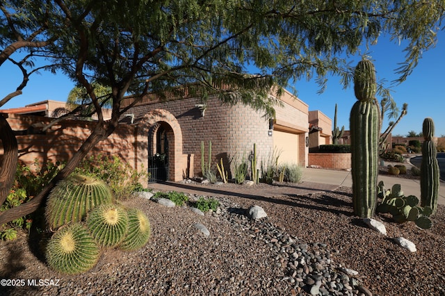 view of front of house with a garage, concrete driveway, and brick siding