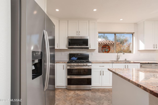 kitchen with appliances with stainless steel finishes, white cabinets, and a sink