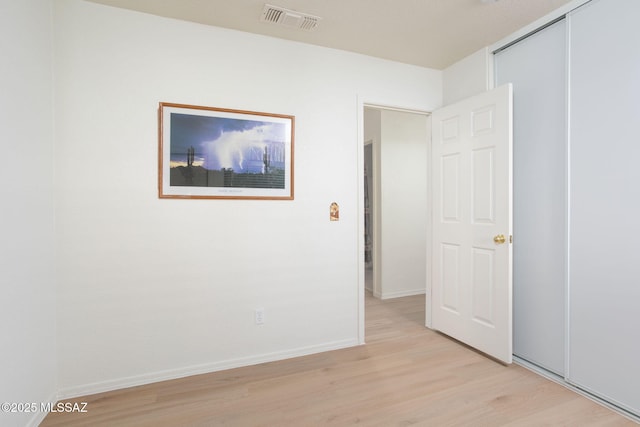 unfurnished bedroom featuring baseboards, a closet, visible vents, and light wood-style floors