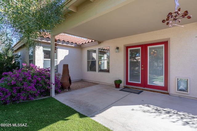 doorway to property featuring french doors, a patio area, a tiled roof, and stucco siding