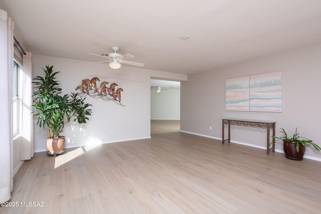 unfurnished living room with ceiling fan, light wood finished floors, and baseboards