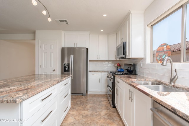 kitchen featuring visible vents, appliances with stainless steel finishes, white cabinets, a sink, and light stone countertops