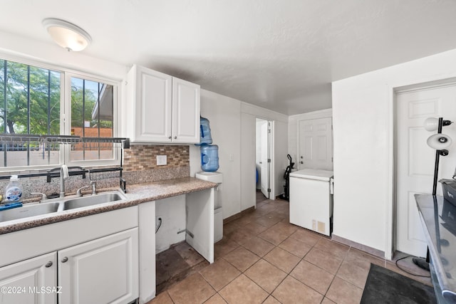 kitchen with refrigerator, a sink, white cabinets, light countertops, and backsplash