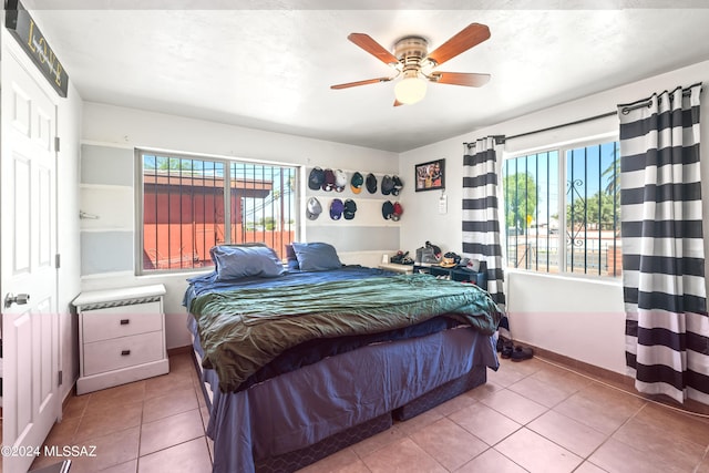 tiled bedroom with ceiling fan and baseboards