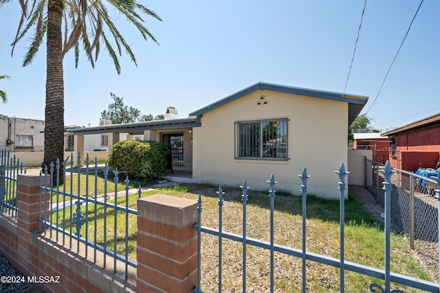 bungalow-style house with a fenced front yard, a front yard, a gate, and stucco siding