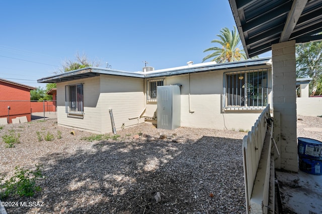 back of house featuring fence and brick siding