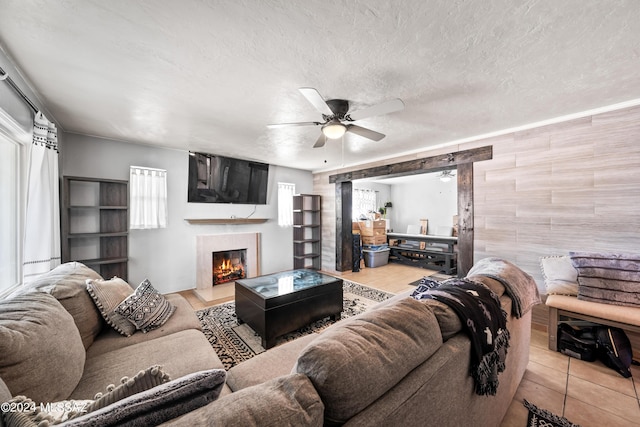 living area featuring a textured ceiling, tile patterned floors, a high end fireplace, and a ceiling fan