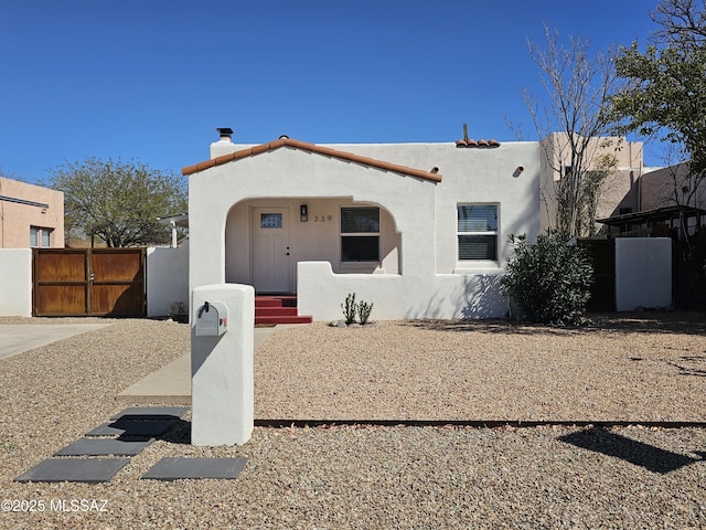 view of front of house with stucco siding, fence, and a gate