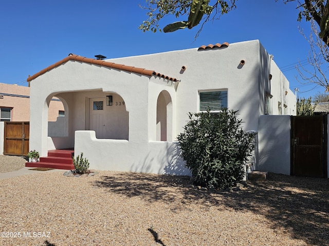 mediterranean / spanish house with stucco siding, a tiled roof, and a gate