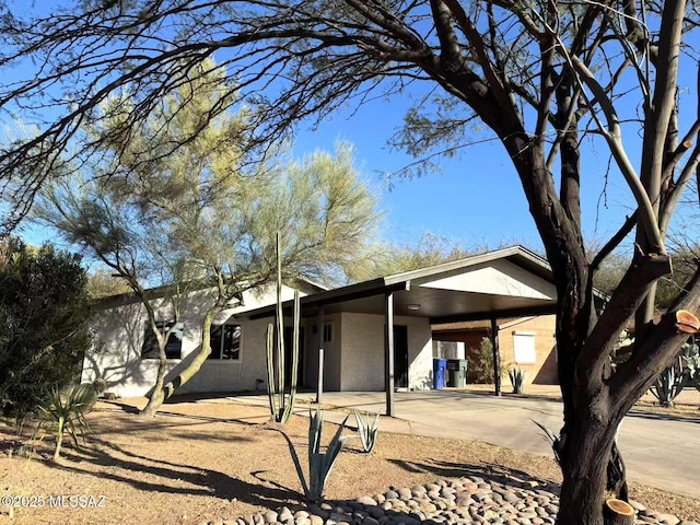 view of front facade with an attached carport, concrete driveway, and stucco siding