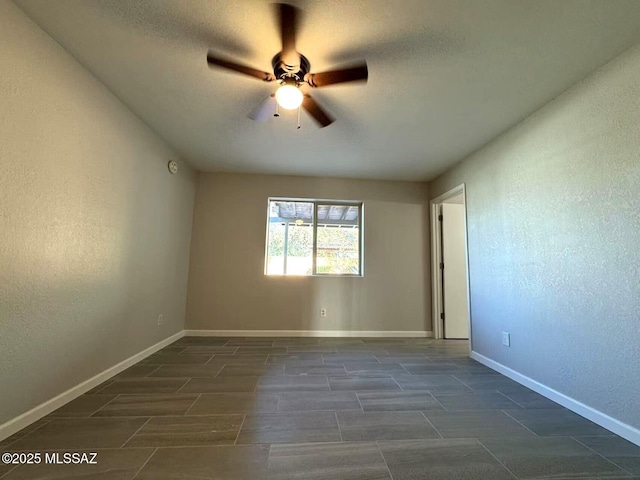 empty room featuring a textured wall, a textured ceiling, baseboards, and ceiling fan