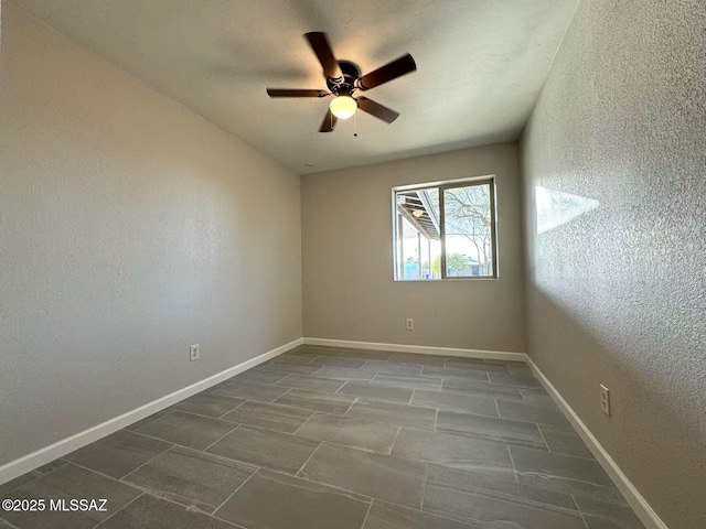 unfurnished room featuring a textured wall, a ceiling fan, and baseboards