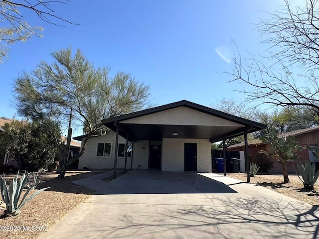 view of front of house with a carport, concrete driveway, and stucco siding