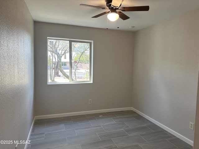 unfurnished room with ceiling fan and baseboards