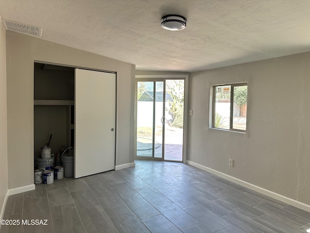 unfurnished bedroom with access to exterior, baseboards, visible vents, and a textured ceiling