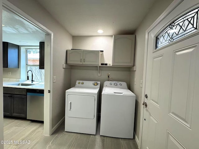 laundry room with washing machine and dryer, wood finish floors, a sink, baseboards, and cabinet space