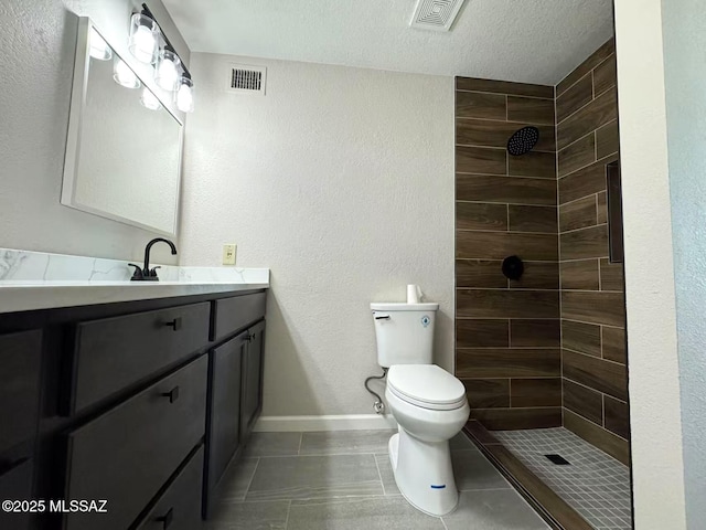 bathroom with visible vents, a tile shower, vanity, and toilet