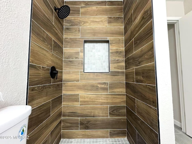 bathroom featuring toilet and a tile shower