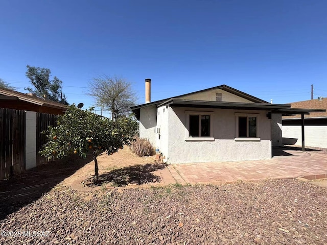 rear view of house with a patio and stucco siding