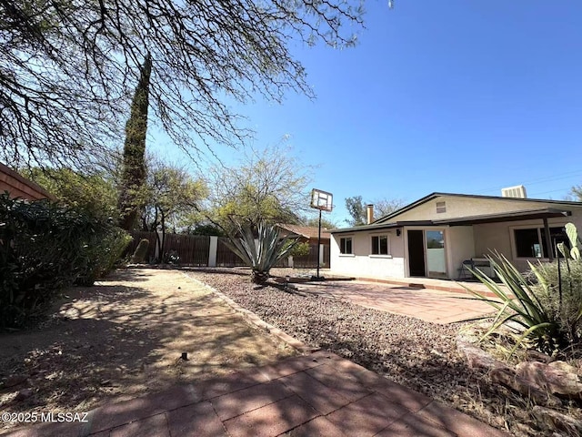 back of property featuring stucco siding, fence, and a patio