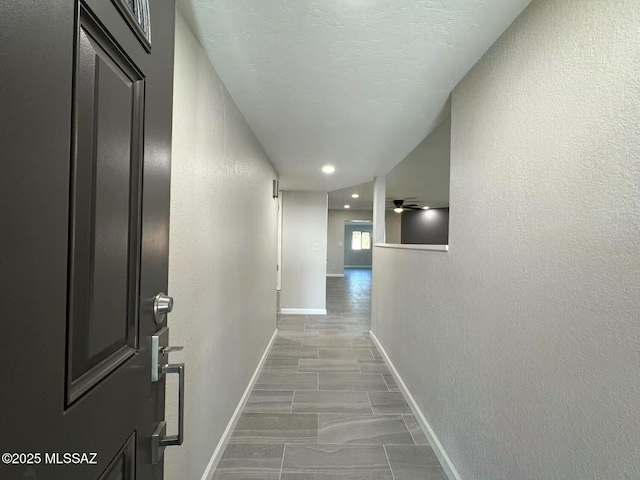 corridor with recessed lighting, baseboards, and a textured wall