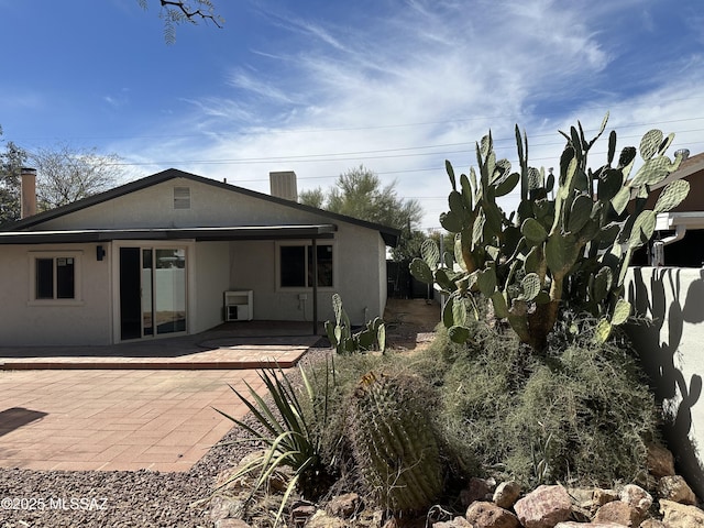 rear view of property featuring cooling unit, a patio, and stucco siding