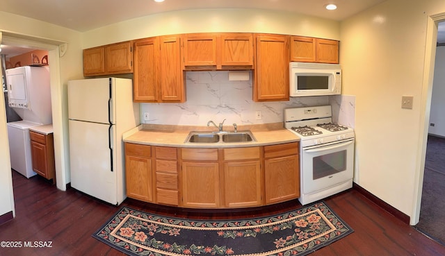 kitchen with stacked washer and dryer, white appliances, light countertops, and a sink