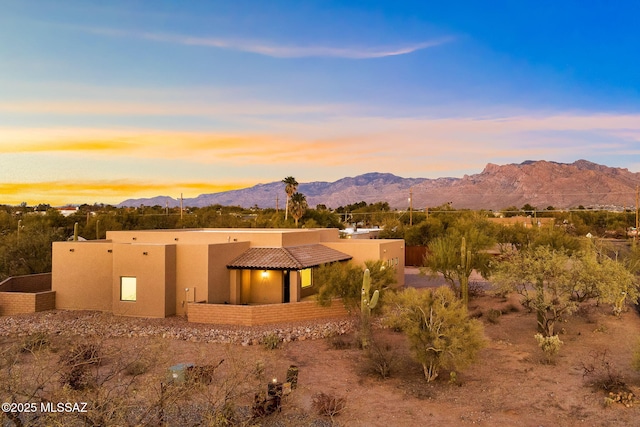 exterior space featuring a tiled roof, a mountain view, and stucco siding