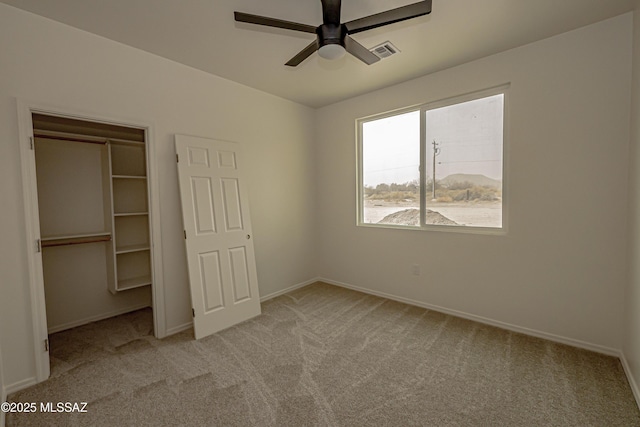 unfurnished bedroom featuring visible vents, baseboards, a closet, a ceiling fan, and light carpet