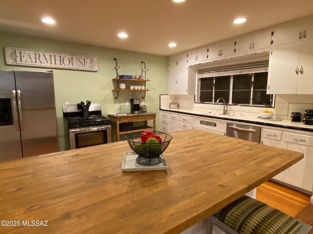 kitchen with wooden counters, appliances with stainless steel finishes, backsplash, and white cabinets