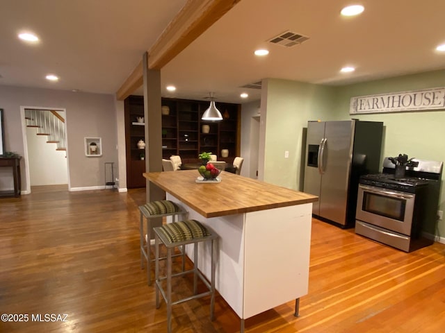 kitchen featuring stainless steel appliances, wood finished floors, wood counters, and visible vents